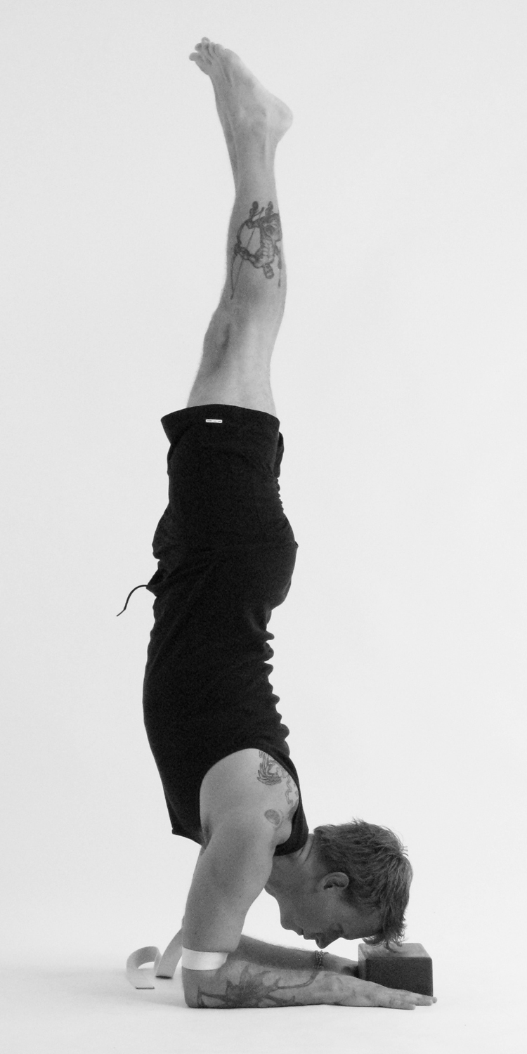 Man doing a Pincha Mayurasana yoga pose or Forearm Balance Stock Photo